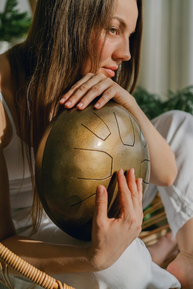 A serene woman with a steel tongue drum, embracing music and mindfulness indoors.